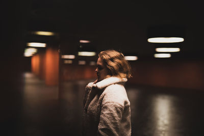 Young woman looking away while standing in garage