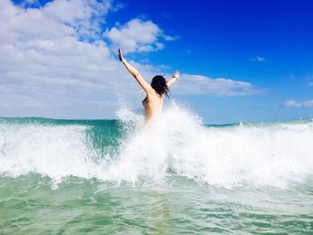 Woman jumping in swimming pool against sky
