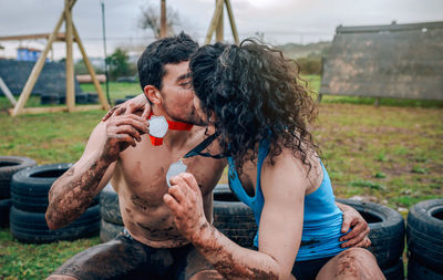 Couple showing medals kissing while sitting outdoors