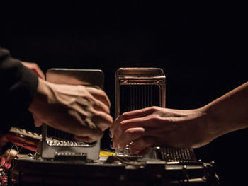 Cropped hands playing music against black background