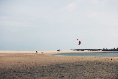 Man flying over beach against sky