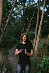 Portrait of young man using camera in forest
