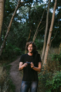 Portrait of young woman using mobile phone in forest