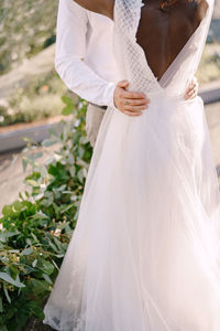 Midsection of woman standing against white wall