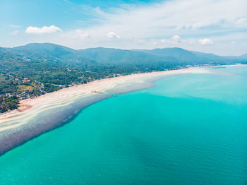 Scenic view of sea by mountains against sky