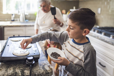 Young boy cooking pancakes with multigenerational family