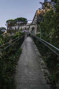 Footbridge over canal amidst buildings against sky