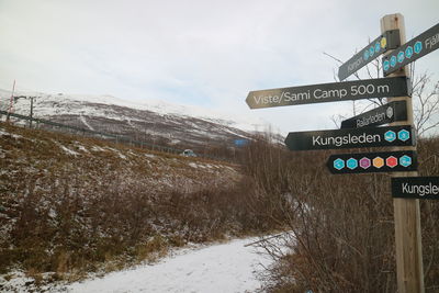 Road signs on snow covered mountain against sky