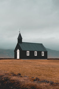 Wooden church on field against sky