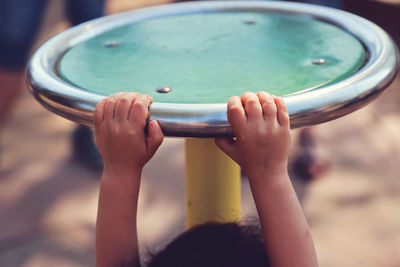 Cropped image of playful girl hanging on outdoor play equipment