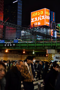 People on illuminated street in city at night