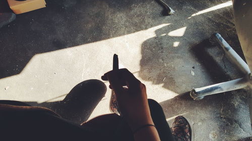 Low section of person holding cigarette on floor