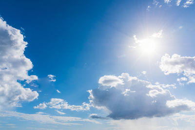 Low angle view of sunlight streaming through clouds