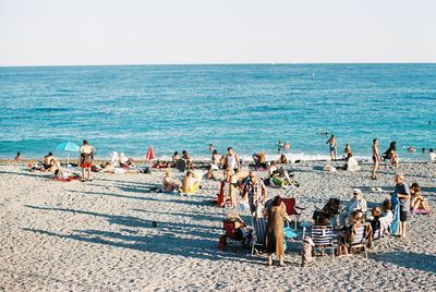 Group of people on beach against clear sky
