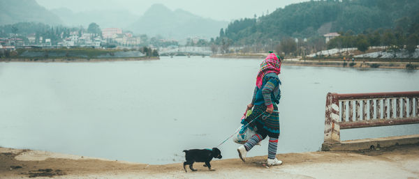 Side view of woman with dog walking by lake