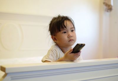 Girl watching tv while sitting on bed at home