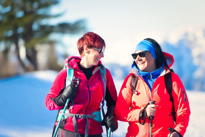 Smiling women walking at ski resort during winter