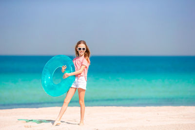 Portrait of girl holding inflatable ring while standing on beach