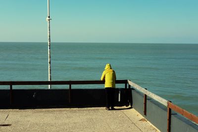 Man standing on pier over sea against sky