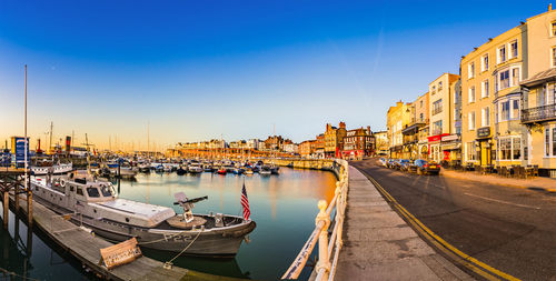 Boats moored in canal by buildings against sky in city