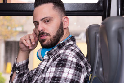 Portrait of young man sitting by window in bus