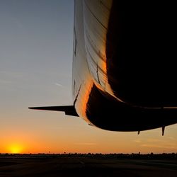 Airplane tail against sky during sunset