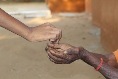 Cropped hand giving coin to female beggar on footpath