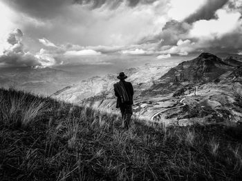 Rear view of man walking on landscape against sky