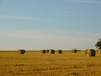 Hay bales on field against sky