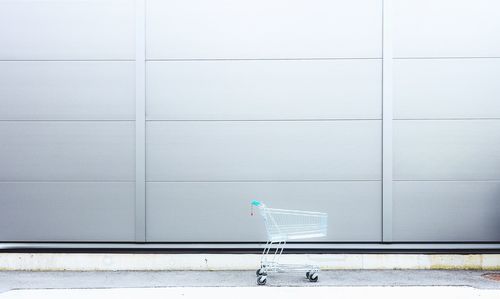 Empty shopping cart against gray wall