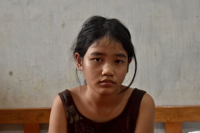 Portrait of young woman looking away against wall