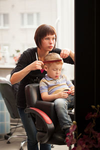 Boy getting haircut from young woman at salon
