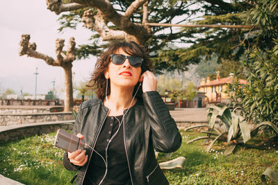 Portrait of smiling mid adult woman using mobile phone on footpath