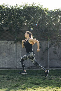 Full length side view of determined female athlete running at park