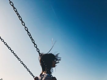Low angle view of woman on swing against sky