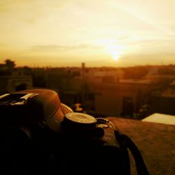 Close-up of hand against cityscape during sunset