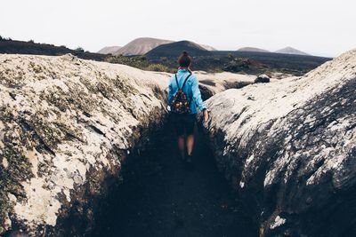 Rear view of woman an standing on mountain against sky