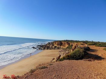 Scenic view of beach against clear blue sky