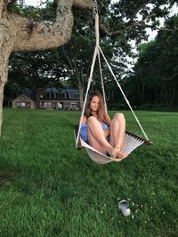 Portrait of smiling young woman sitting on hammock at park