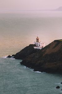 Lighthouse by sea against sky