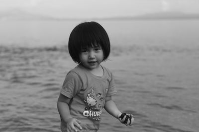 Portrait of cute girl with sand on beach against sea