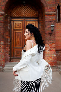 Portrait of woman standing against door