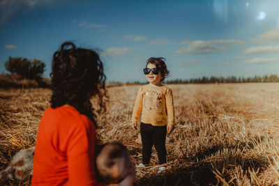 Children standing on field against sky