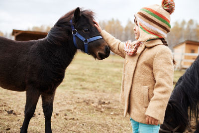 Little girl stroking lovely pony