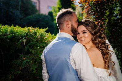 Newlywed couple embracing while standing outdoors