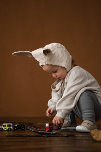 Toddler baby boy in funny bunny hat playing with toy car