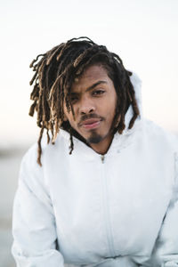 Portrait of confident man with dreadlocks wearing hooded jacket