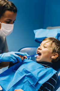 Dentist operating boy in medical clinic