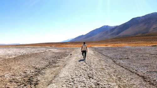 Rear view of woman standing on mountain against clear sky