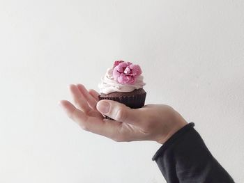 Cropped hand of woman holding rose against white background